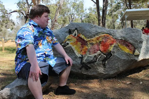 person sitting infront of fox paint mural on stone